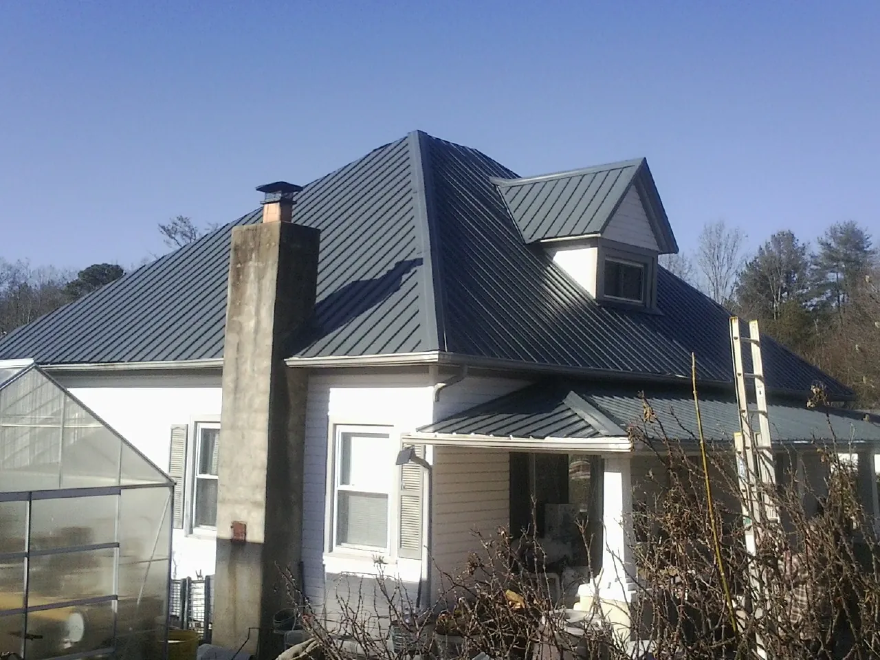 Dark blue standing seam metal roof on a white farmhouse with dormer — Slate & Tile Roof Repair by Roofing Brothers in Mosheim