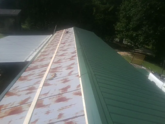 Old rusted panels beside newly installed green metal roofing — Wind Damage Roof Repair by Roofing Brothers in Mosheim