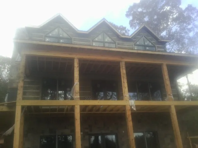 Dormers and porch framing on a large log home under construction — Roof Coating work by our crew in Mosheim