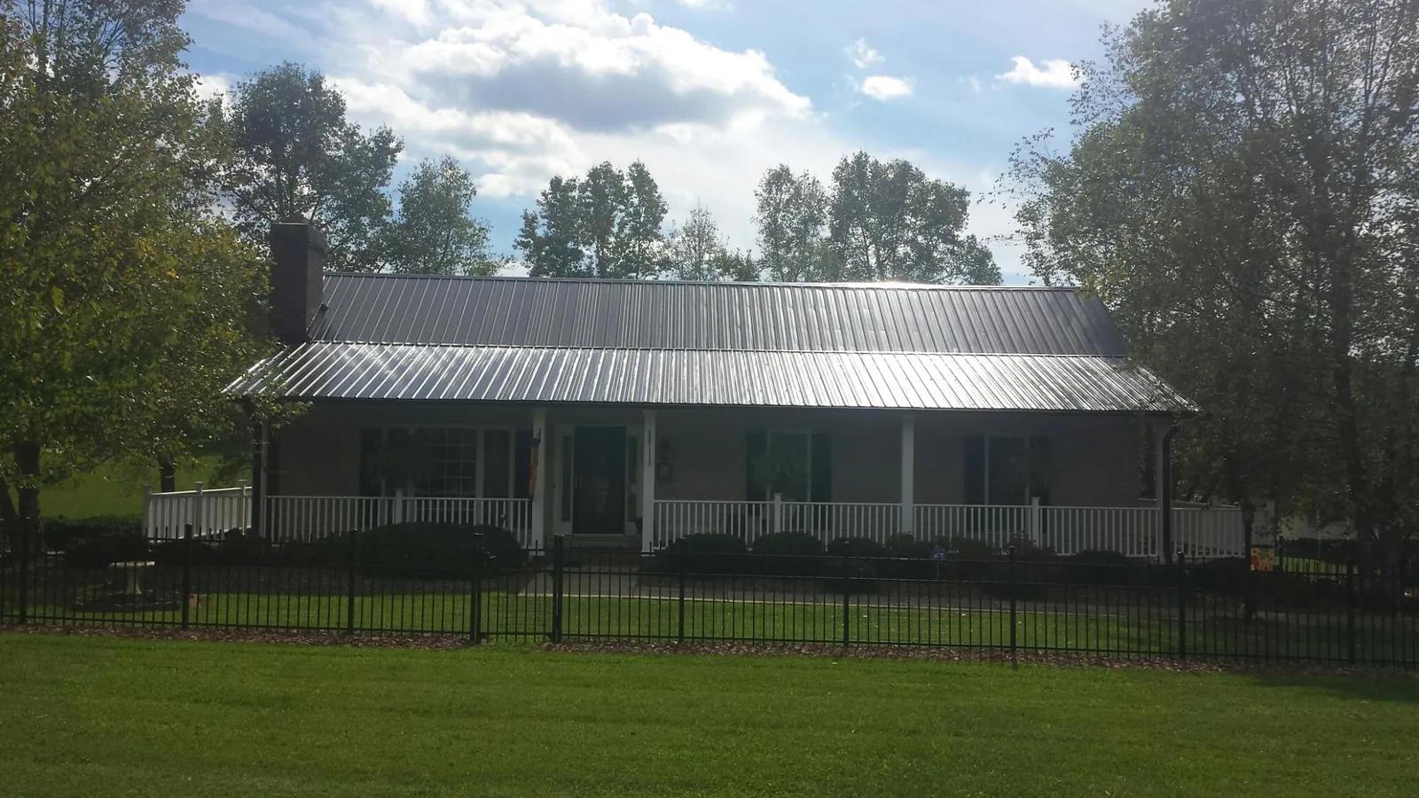 Gray metal roof on a brick ranch with a full width front porch — Gutter Guard Installation work by our crew in Mosheim