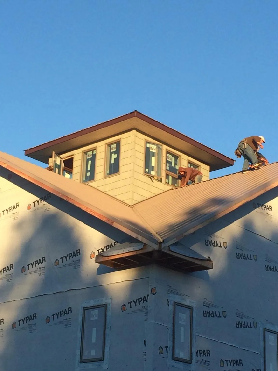 Roofers working around a rooftop cupola on a new metal roof at sunset — Roof Waterproofing in Mosheim by Roofing Brothers